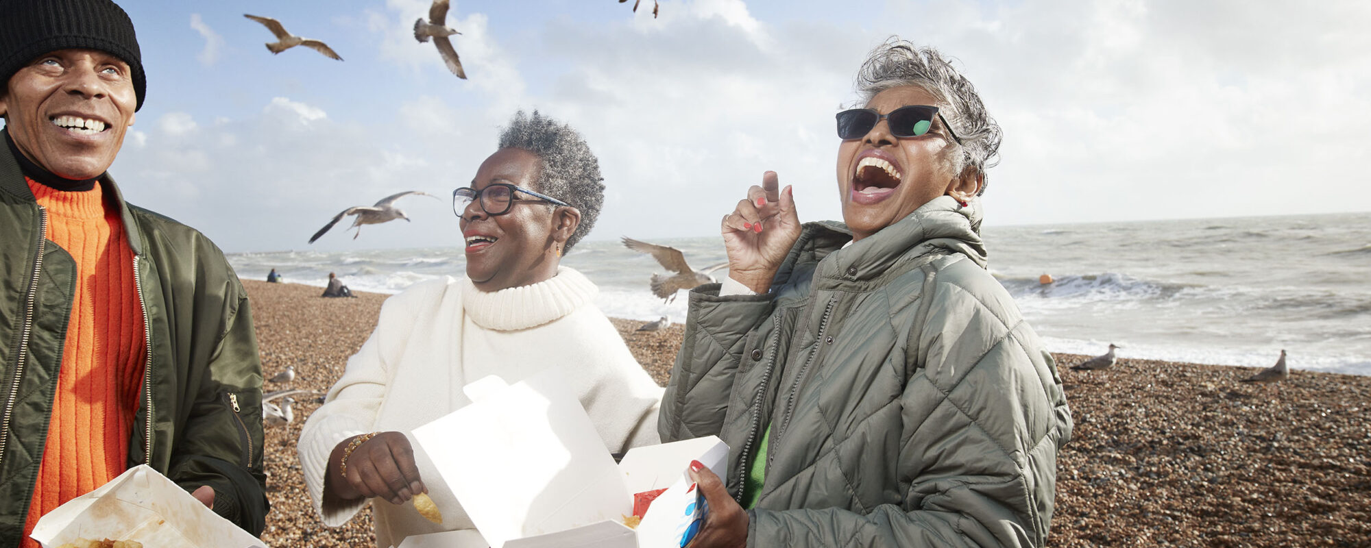 Cheerful senior people with food containers at beach