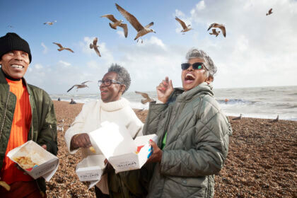 Cheerful senior people with food containers at beach