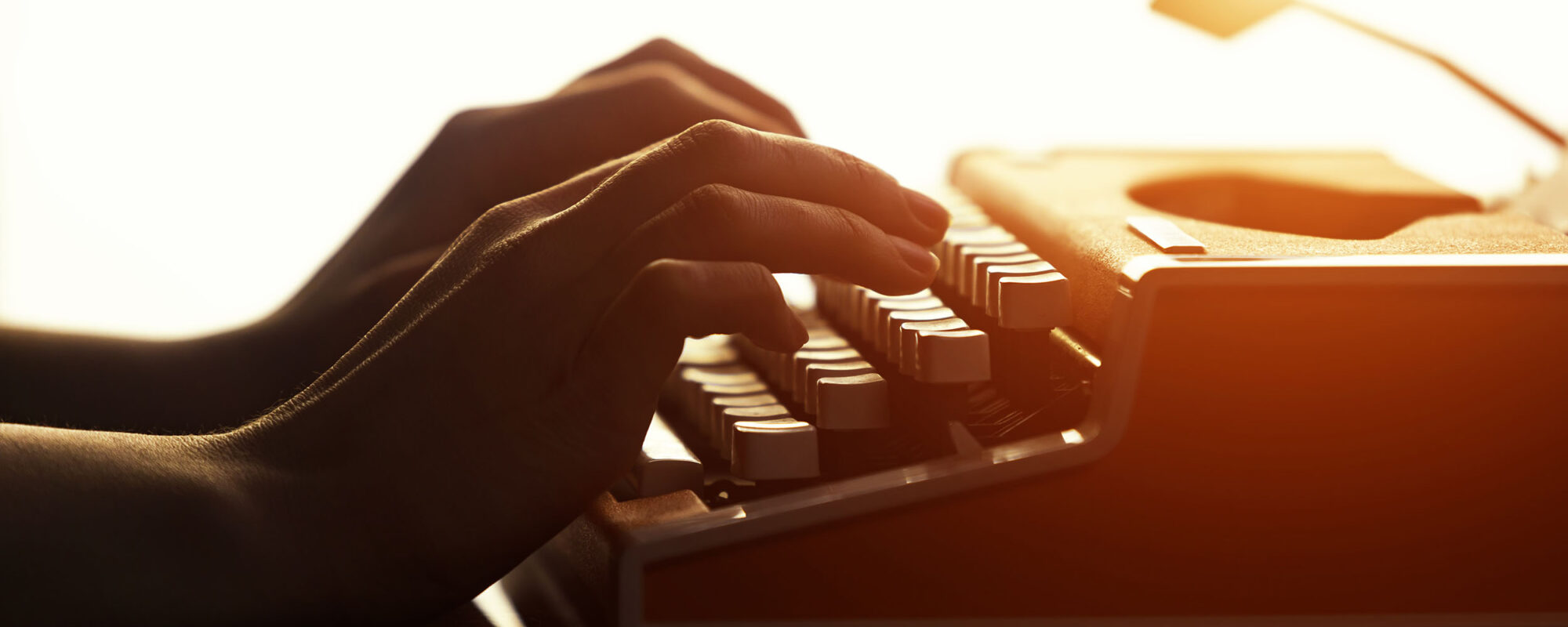 Hands typing on vintage typewriter.