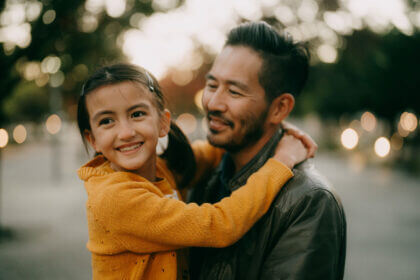 Young girl and her father hugging at dusk