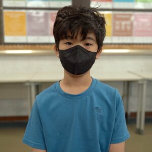 South Korean boy wearing a mask in a classroom.