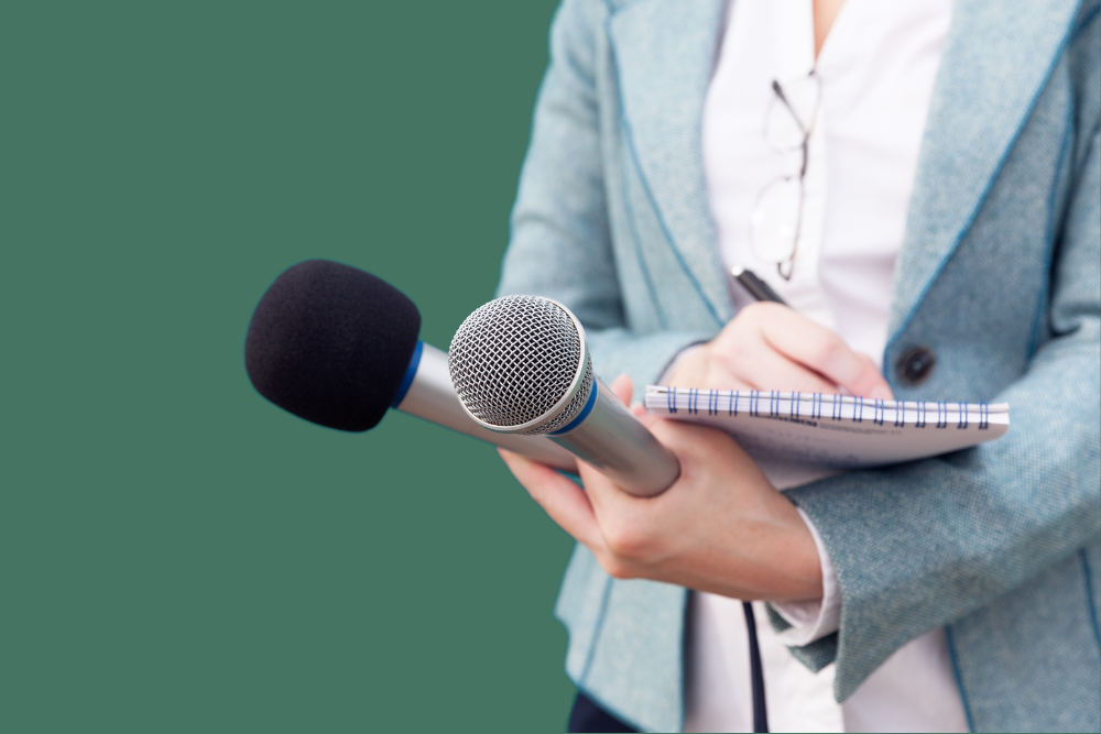 Hand holding microphone, while other hand takes notes.