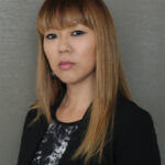 Jenny Town headshot, woman with blonde hair and dark blazer looks at camera with solem expression